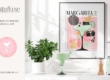 Modern kitchen display with Sugarluxe branding, home decor, and a framed cocktail art print. There is a countertop with a green succulent plant in a white pot, a green frozen margarita in a glass with salt on the rim, and a light green Smeg blender. Behind these objects is a framed art piece depicting a stylized margarita glass with abstract decorative elements and the word "MARGARITA." The colors in the art are primarily pink, green, and black, aligning with the modern aesthetic.