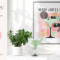 Modern kitchen display with Sugarluxe branding, home decor, and a framed cocktail art print. There is a countertop with a green succulent plant in a white pot, a green frozen margarita in a glass with salt on the rim, and a light green Smeg blender. Behind these objects is a framed art piece depicting a stylized margarita glass with abstract decorative elements and the word "MARGARITA." The colors in the art are primarily pink, green, and black, aligning with the modern aesthetic.